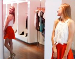 Bilde av en jente som står foran speilet og prøver klær.