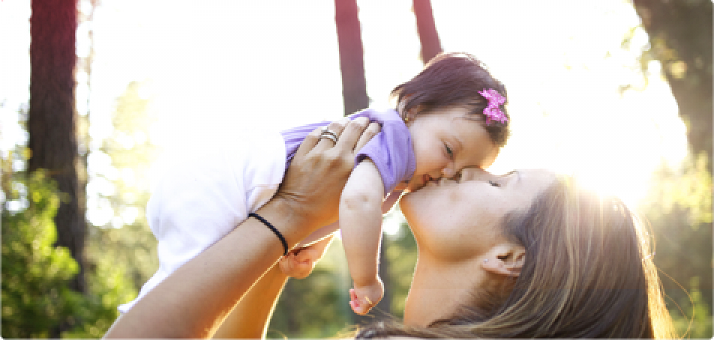 Bilde av en kvinne som kysser og holder en baby.